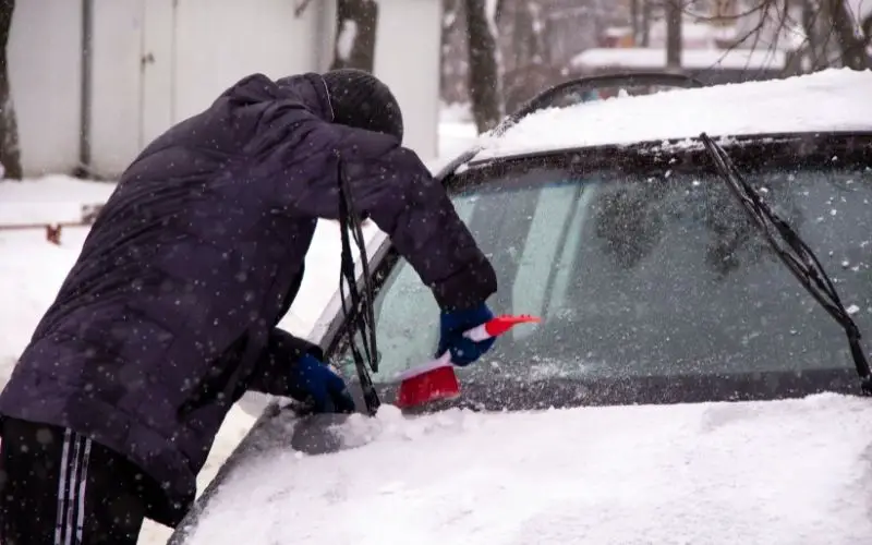 A man cleans his car from snow during winter snowstorms