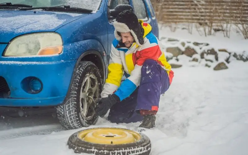 Man Changing a Tire During Winter