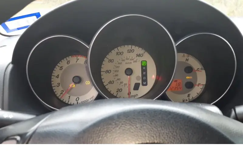 a car dashboard showing the check engine light on the tachometer