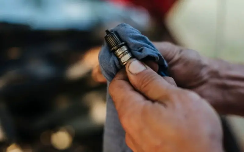 a mechanic cleaning a used spark plug